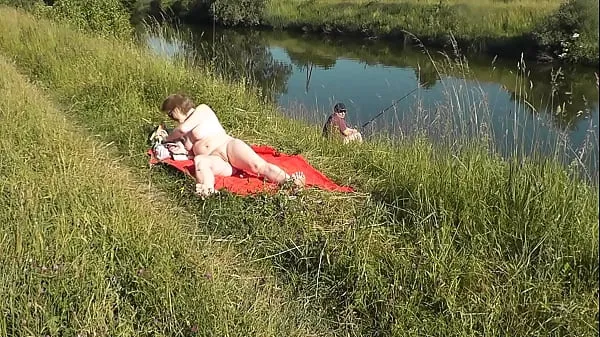 XXX MILF sexy Frina on river bank undressed and sunbathes naked. Random man fisherman watching for her, and in the end decided to join naked woman. Wild beach. Nudist beach. Public nudity. Public exposure. Naked in public topclips